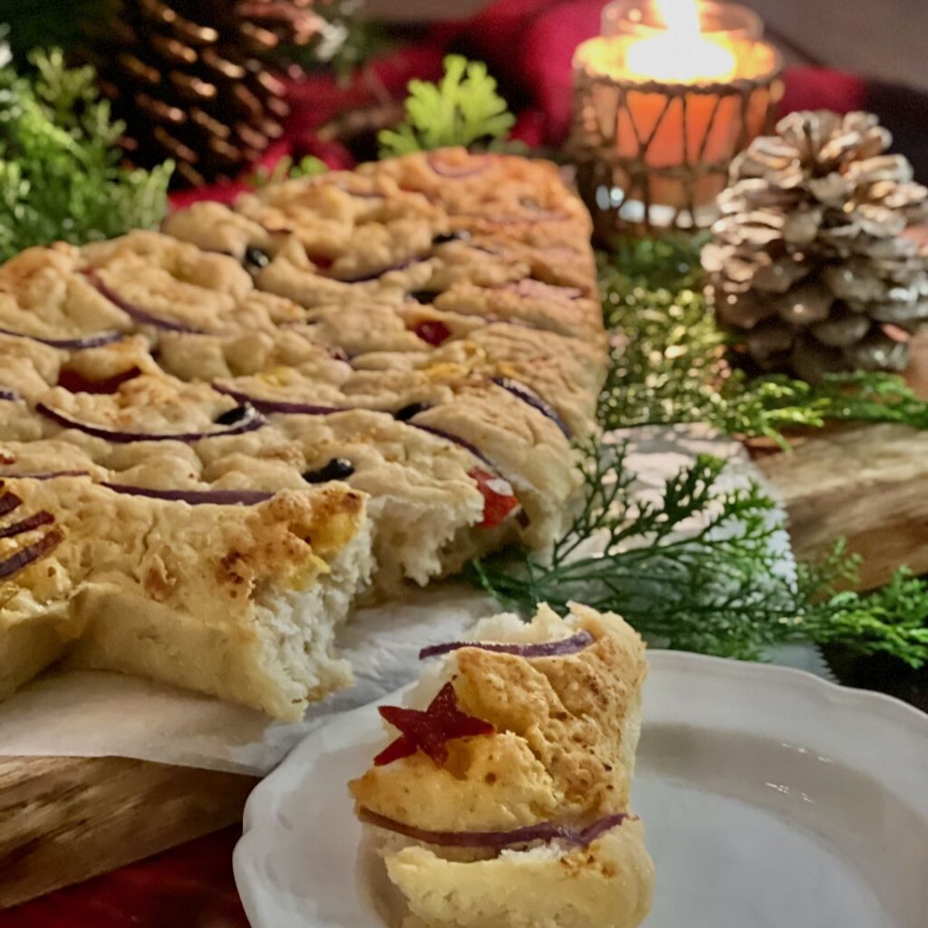 focaccia Christmas tree in the background with a serving of torn focaccia on a plate in foreground