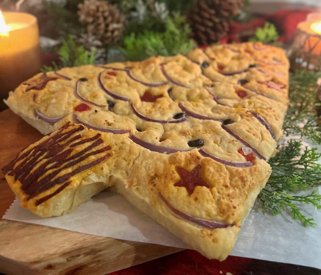 angle view of Christmas tree shaped and decorated focaccia on wood board