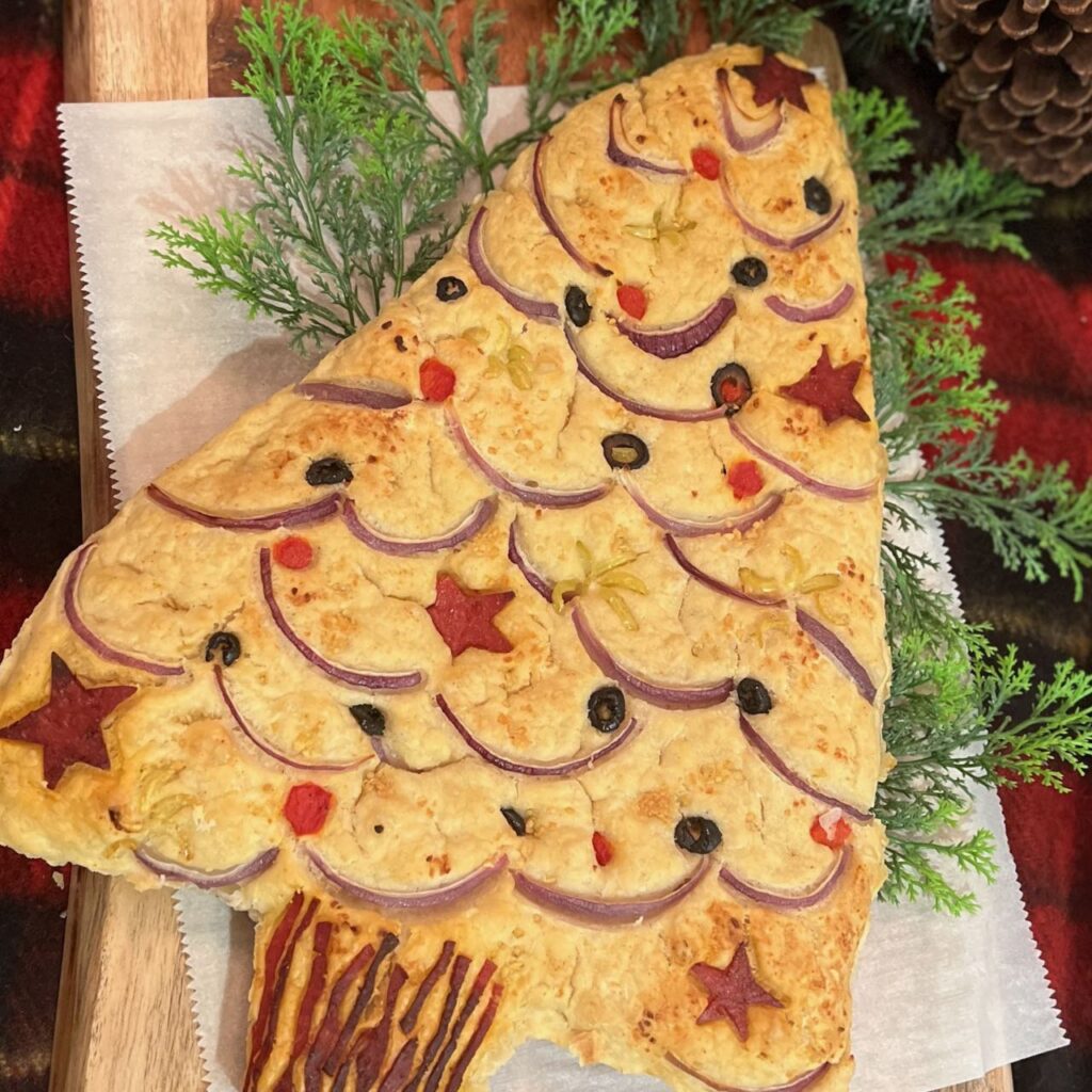 Finished decorated focaccia Christmas tree on a large wood serving board