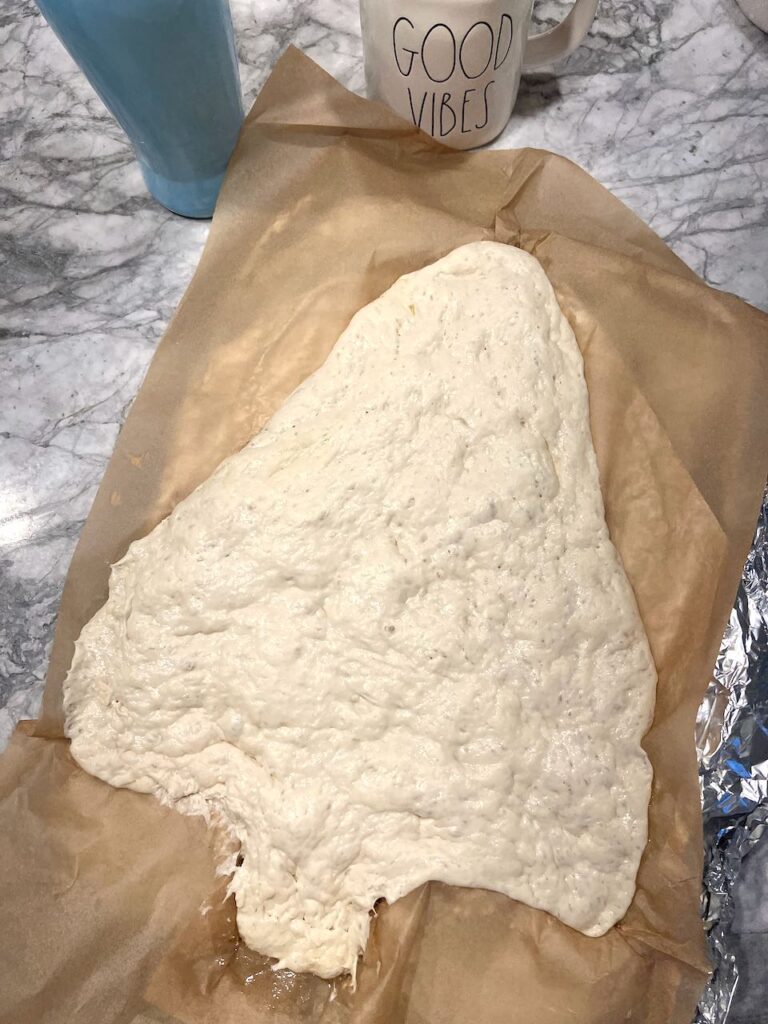 Focaccia dough risen in the parchment lined pan