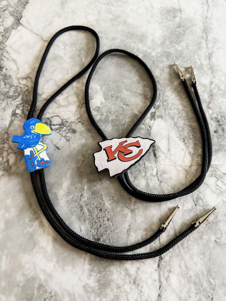 Two finished bolo ties laying on a quartz countertop