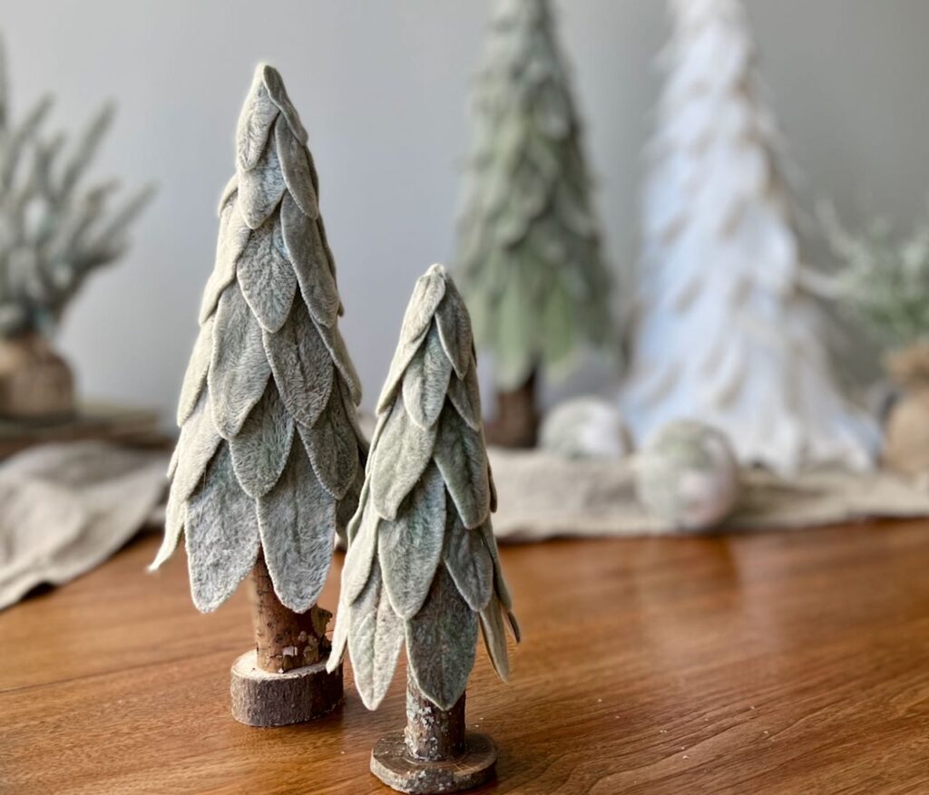 two small lambs ear trees in foreground with large tree and poinsettia tree in background wit linen runner