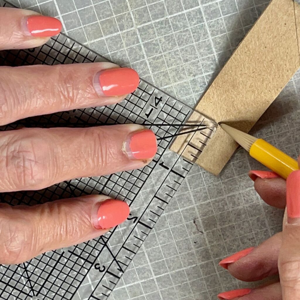 closeup of woman's fingers holding ruler on the folded end of a cardboard ring and marking a spot