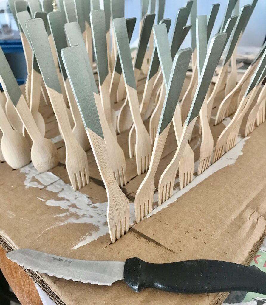 rows of bamboo flatware with green painted handles sticking into the air to dry