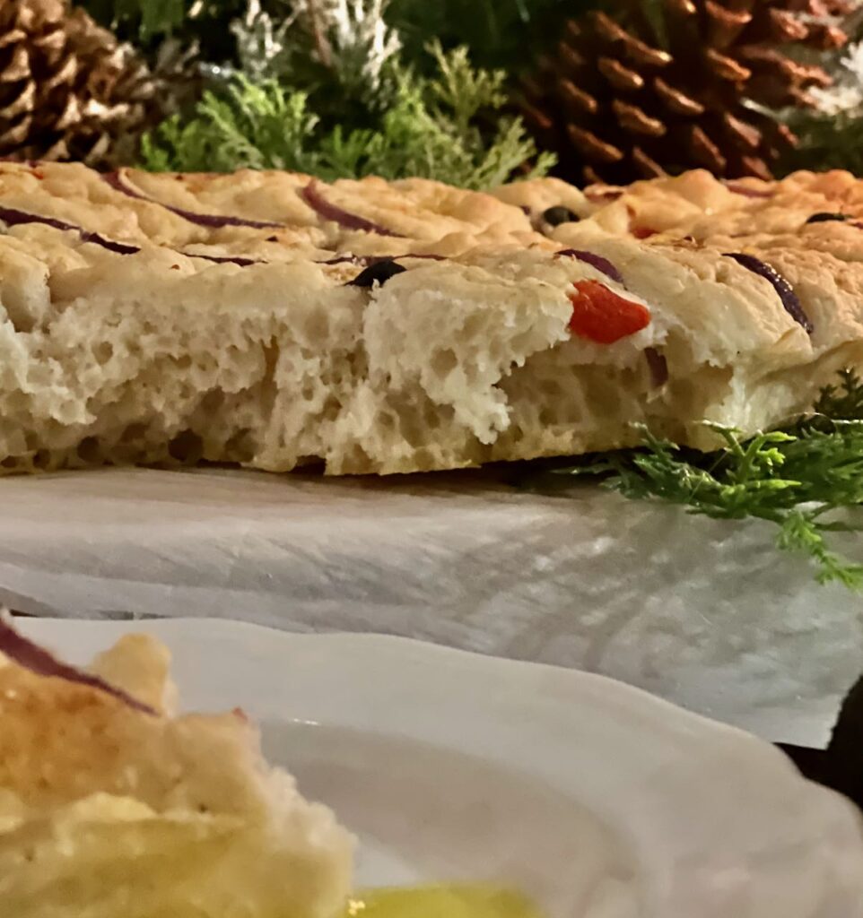 closup of part of a serving with the cross view of the inside of the focccia filled with soft air bubbles