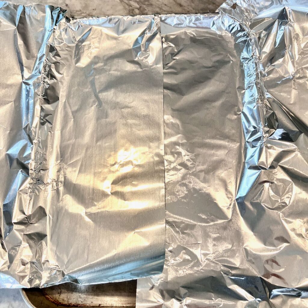 two sheets of foil are on each side of the sheet pan