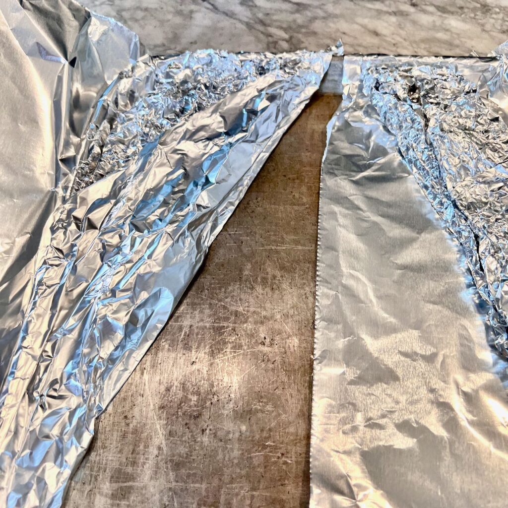 two long triangles of wadded up foil are on top of the foil sheets filling thee corners