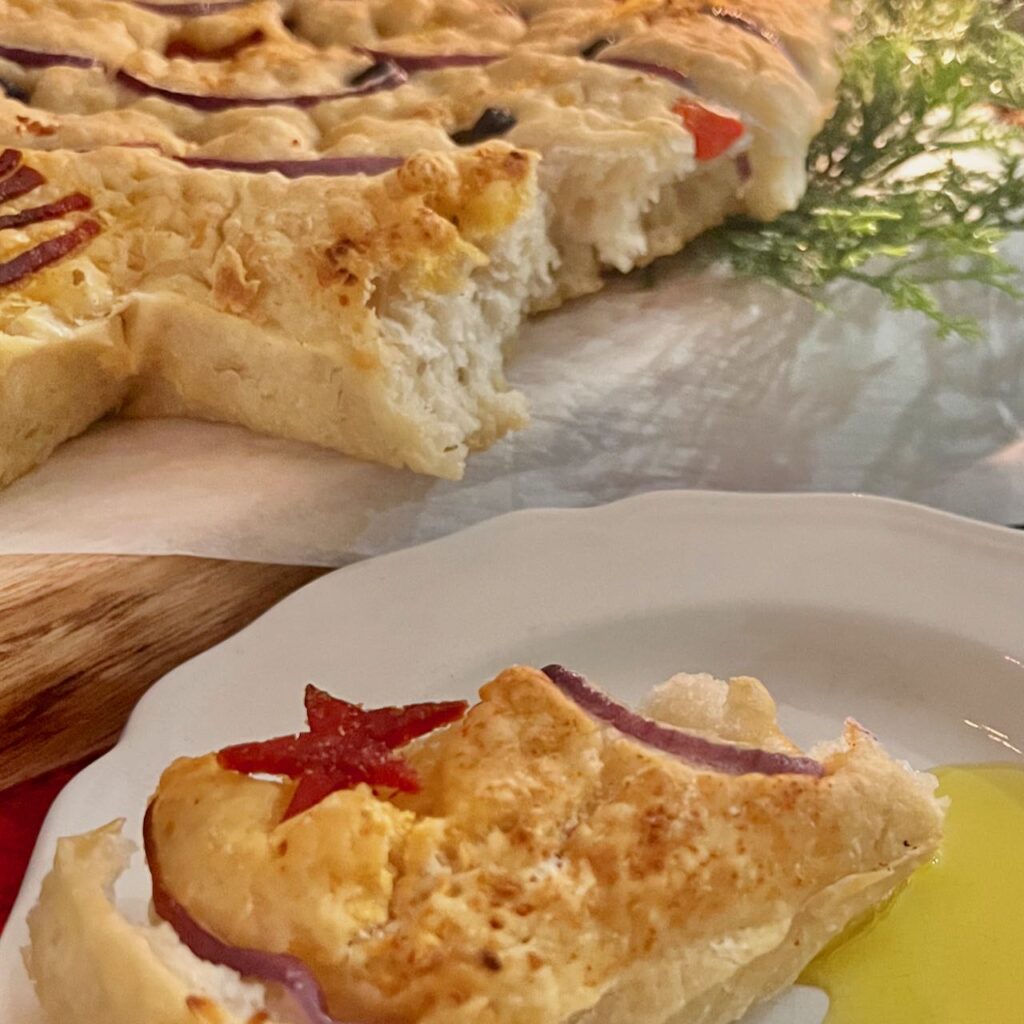 serving of focaccia on a small white plate with a pool of olive oil