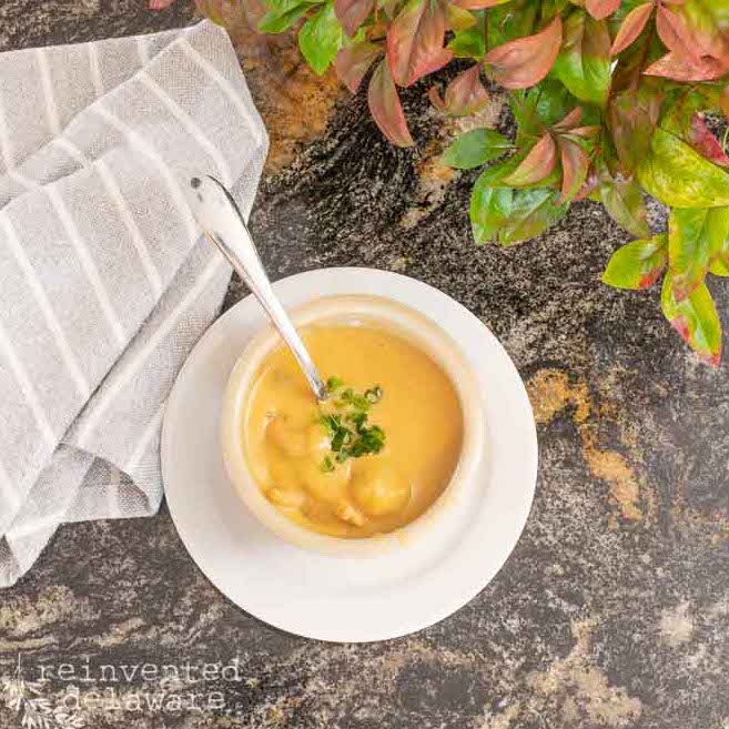 overhesad view of shrimp bisque in a cup with a spoon in it and a napkin beside