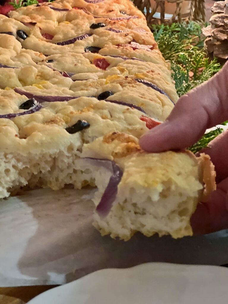 fingers showing tearing a piece of focaccia off the tree