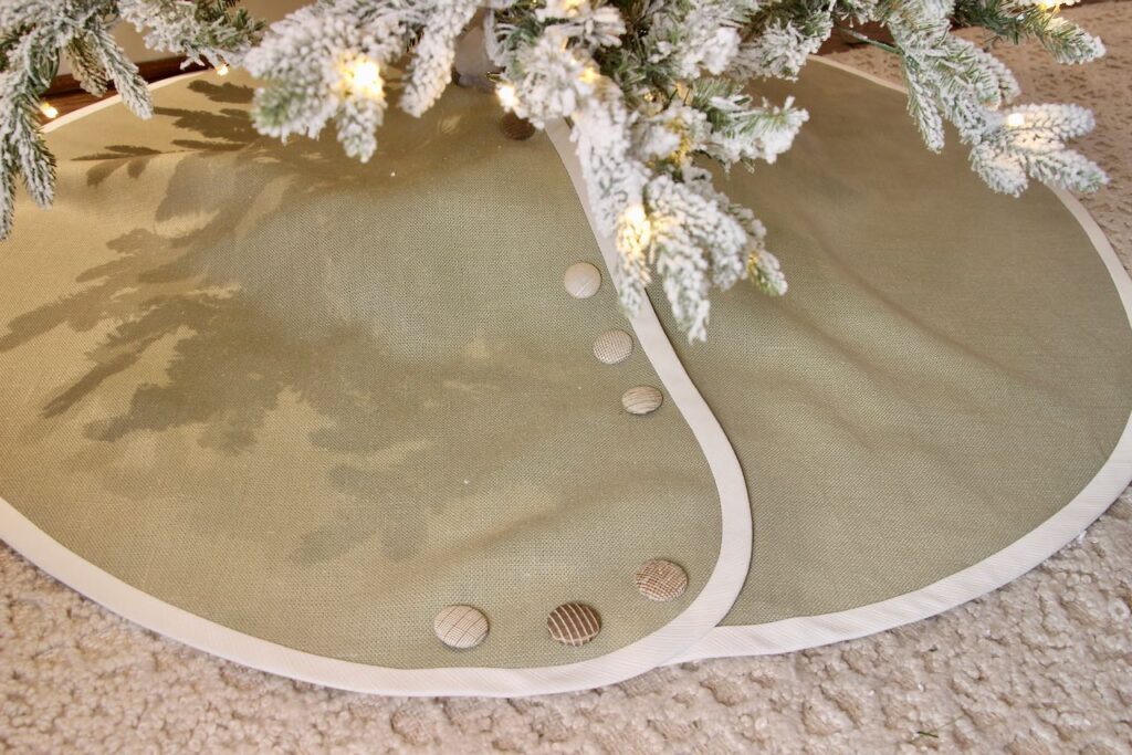 soft green linen tree skirt banded in white is shown under the Christmas tree