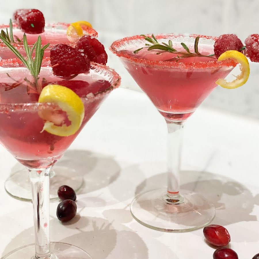 festive cocktail in three martini glasses with fruit garnishes