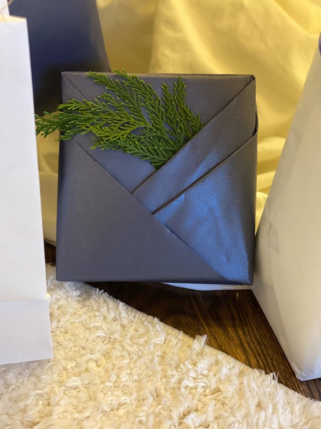Paper wrapped around a package with fresh cedar tucked inside a fold