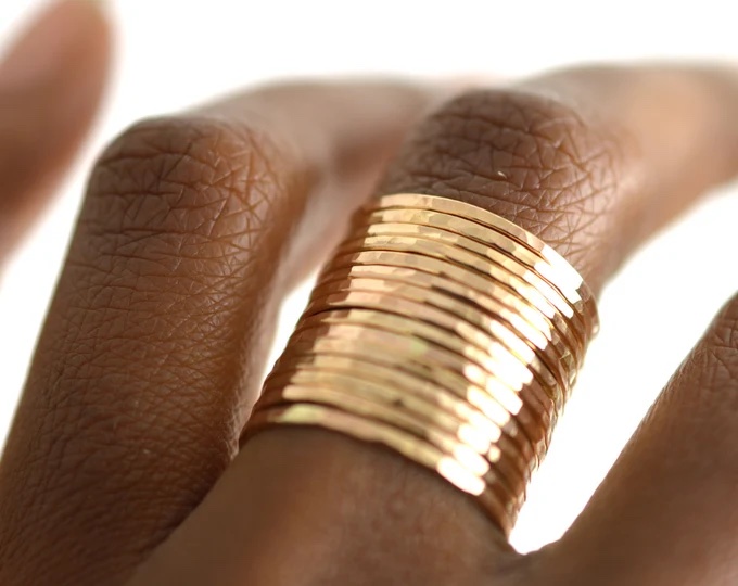 woman's fingers with a whole bunch of vey thin gold rings stacked together