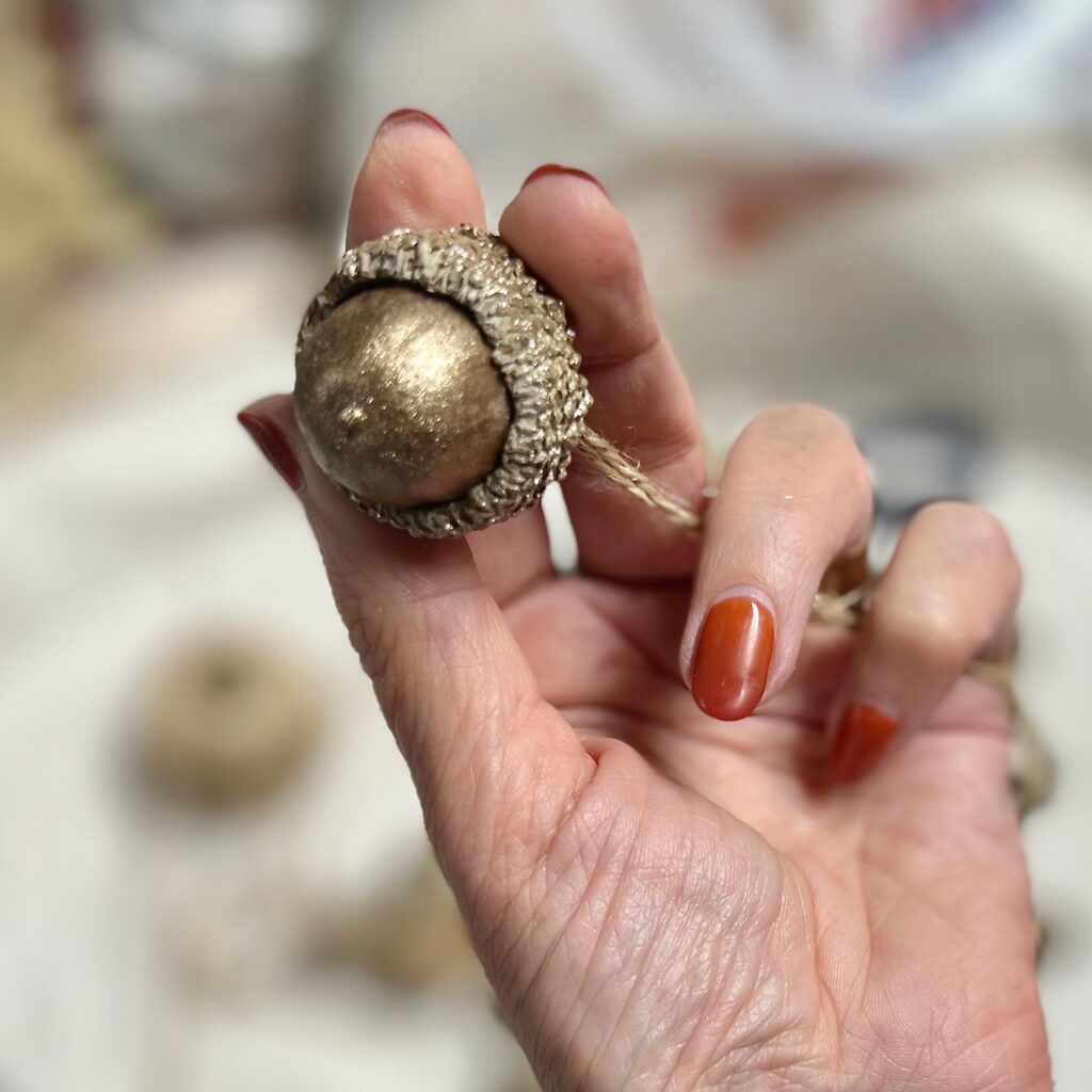 woman's hand holding a metallic bronze painted acorn