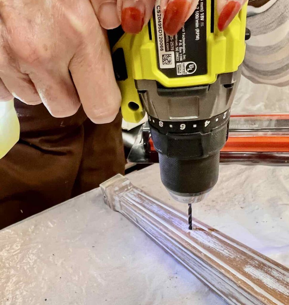 closeup of a woman's hands holding a drill on a bench leg drilling the pilot hole