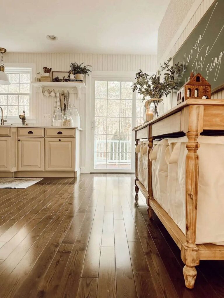 View of a kitchen with a console table a glass door in the background and a open shelf beside it