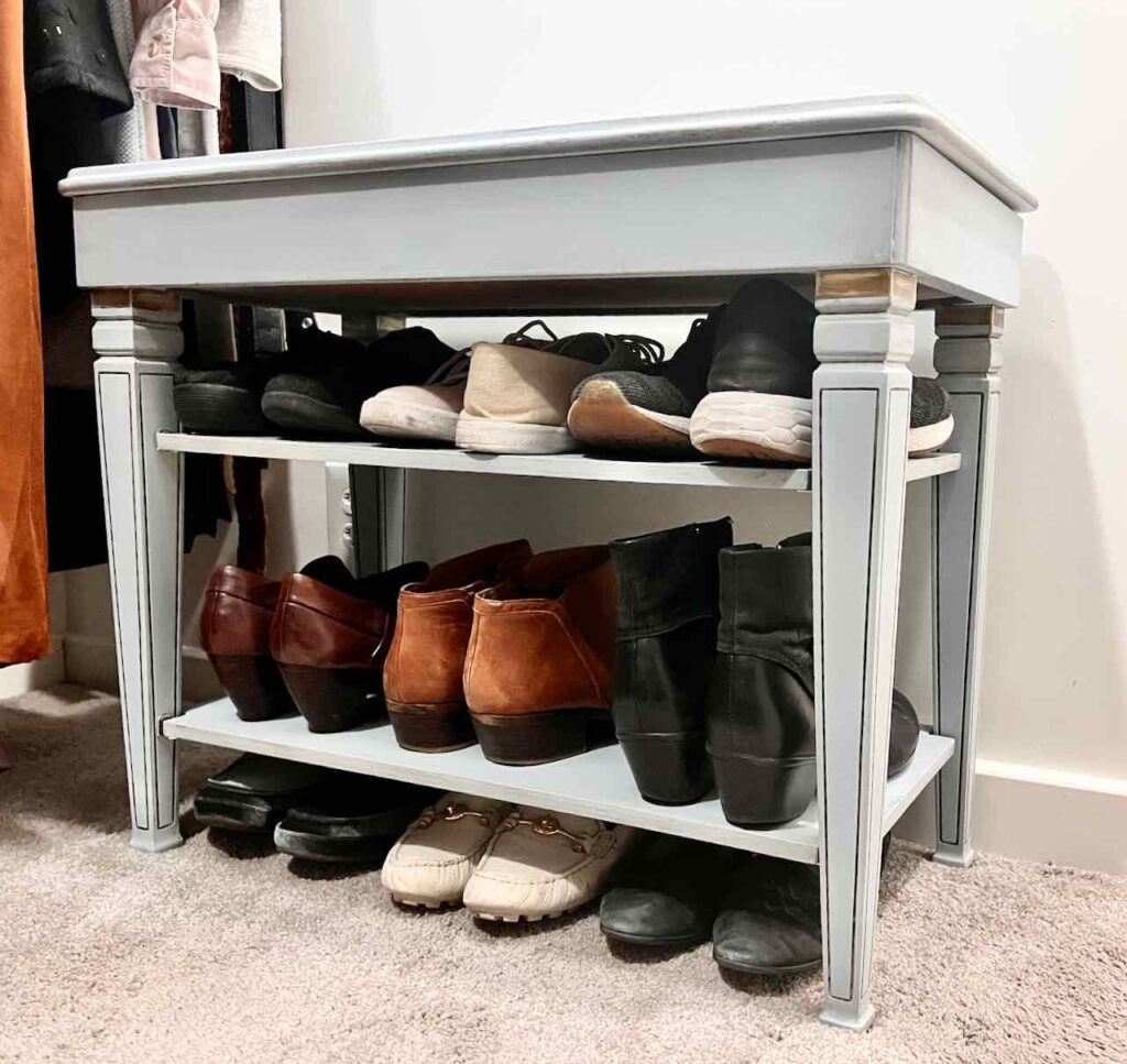 angle view of the finished shoe bench loaded with shoes sitting next to hanging dresses