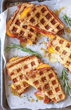 Grilled cheese sandwich halves on a white napkin on a tray with fresh herbs scattered about