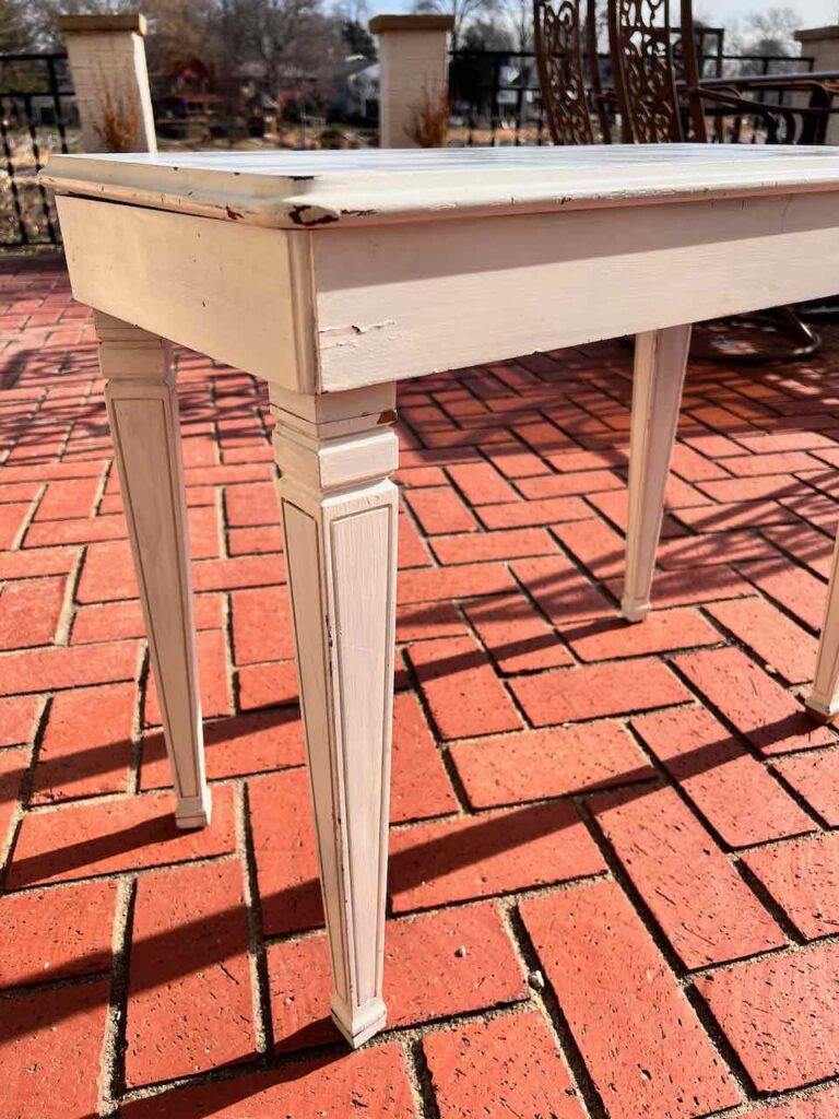 thrifted and battered piano bench is sitting on a brick patio