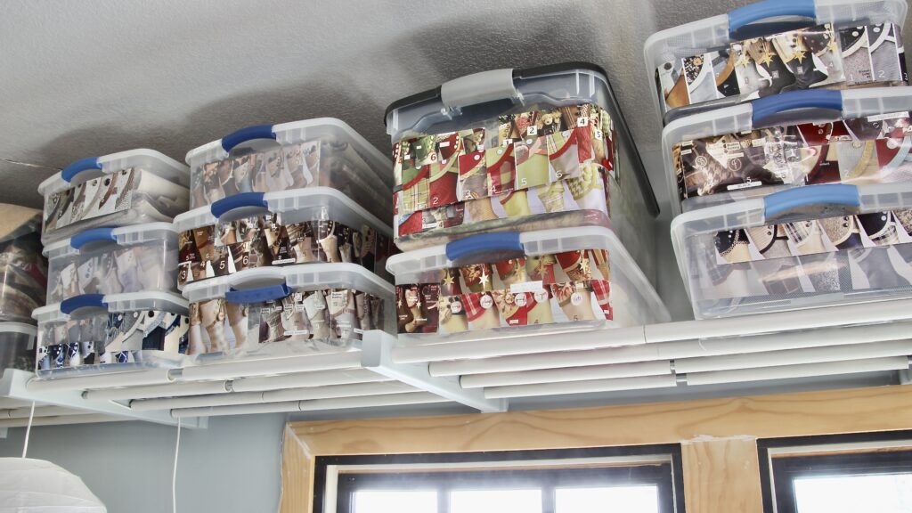 view from below of plastic storage tubs stacked on a DIY'd overhead storage rack