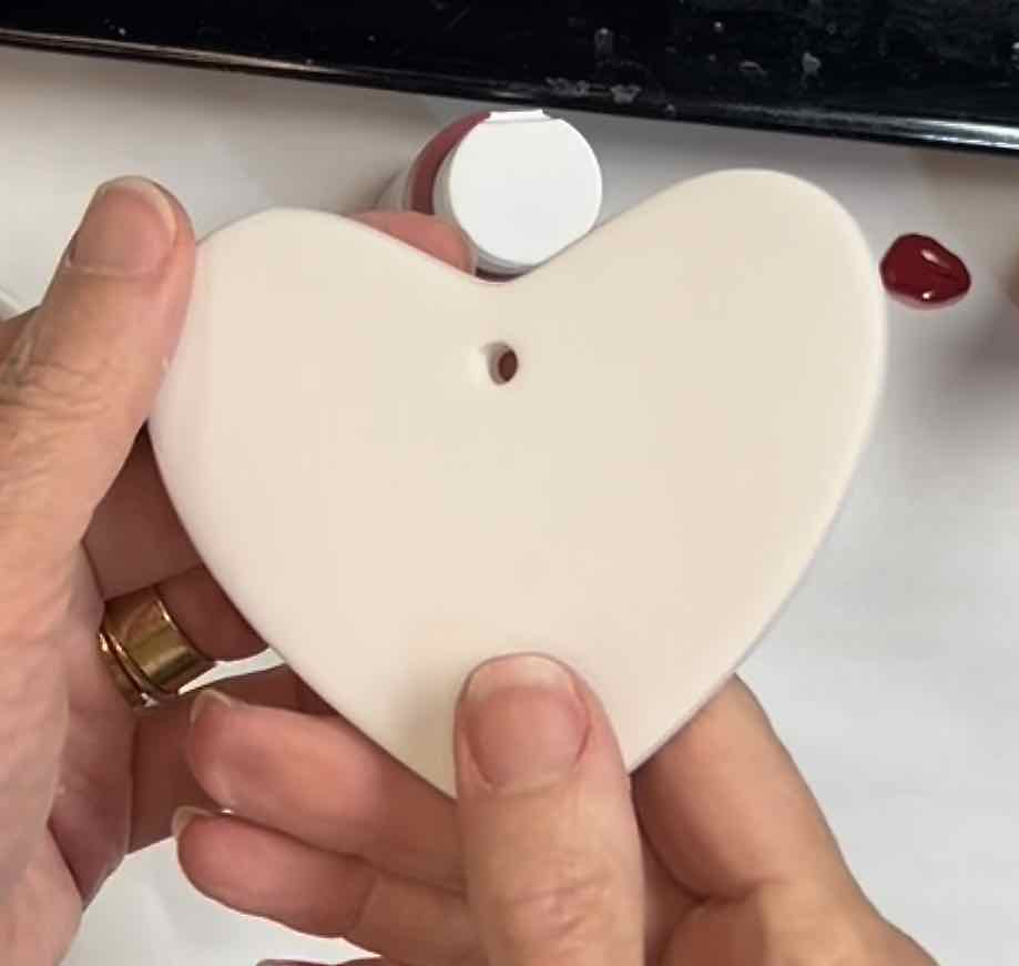 closeup of two hands holding a white blank ceramic heart