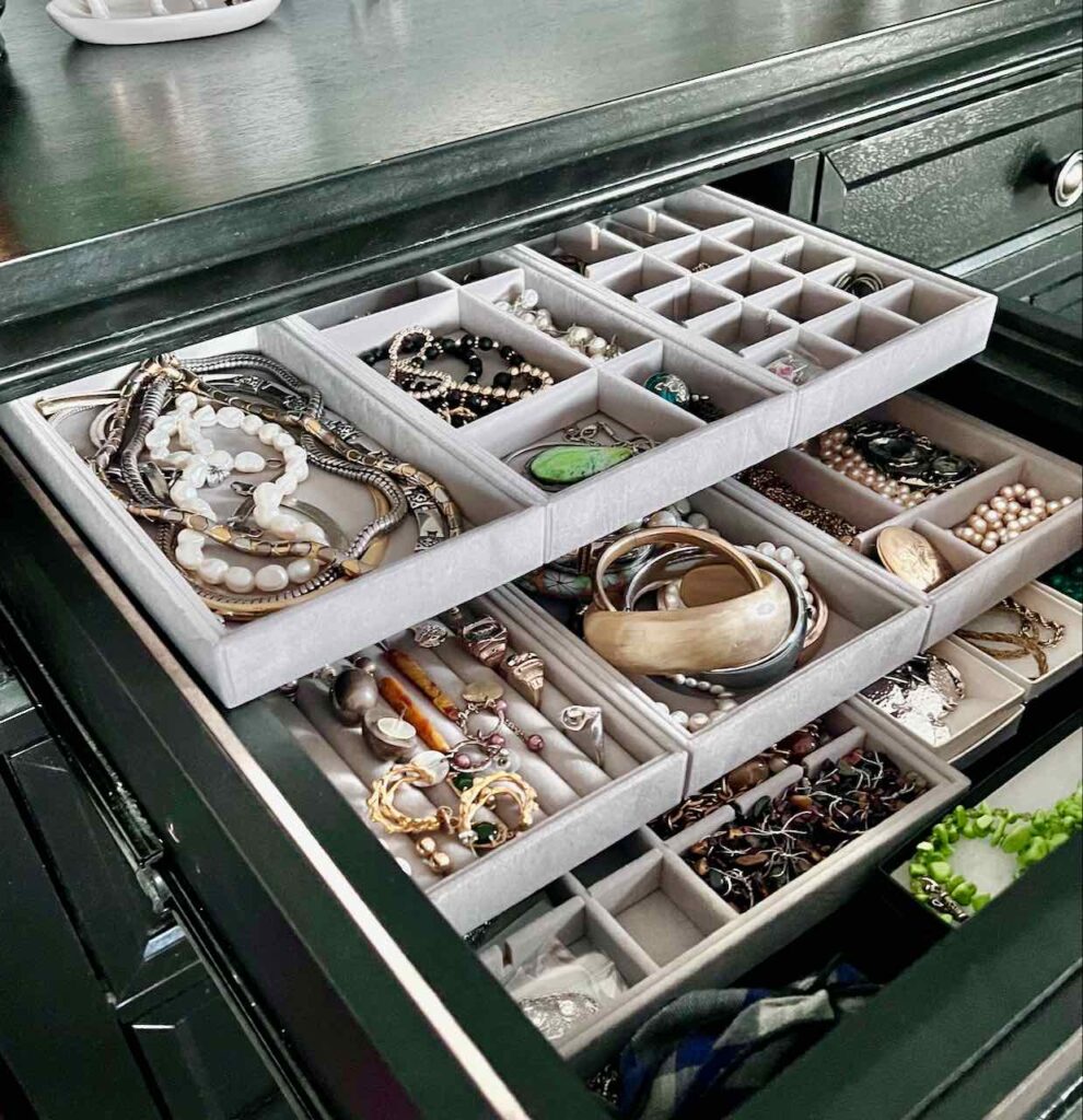 dresser drawer is open revealing three layers of sliding jewelry trays