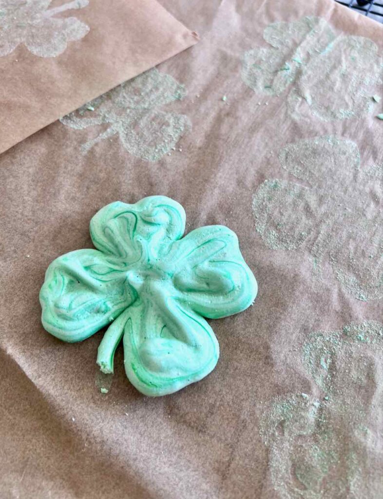 single lonely shamrock meringue cookie is left behind on the parchment paper