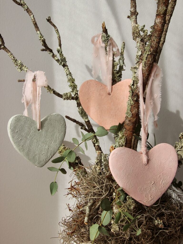 Three finished hearts in different colors all hanging from frayed chiffon ribbon