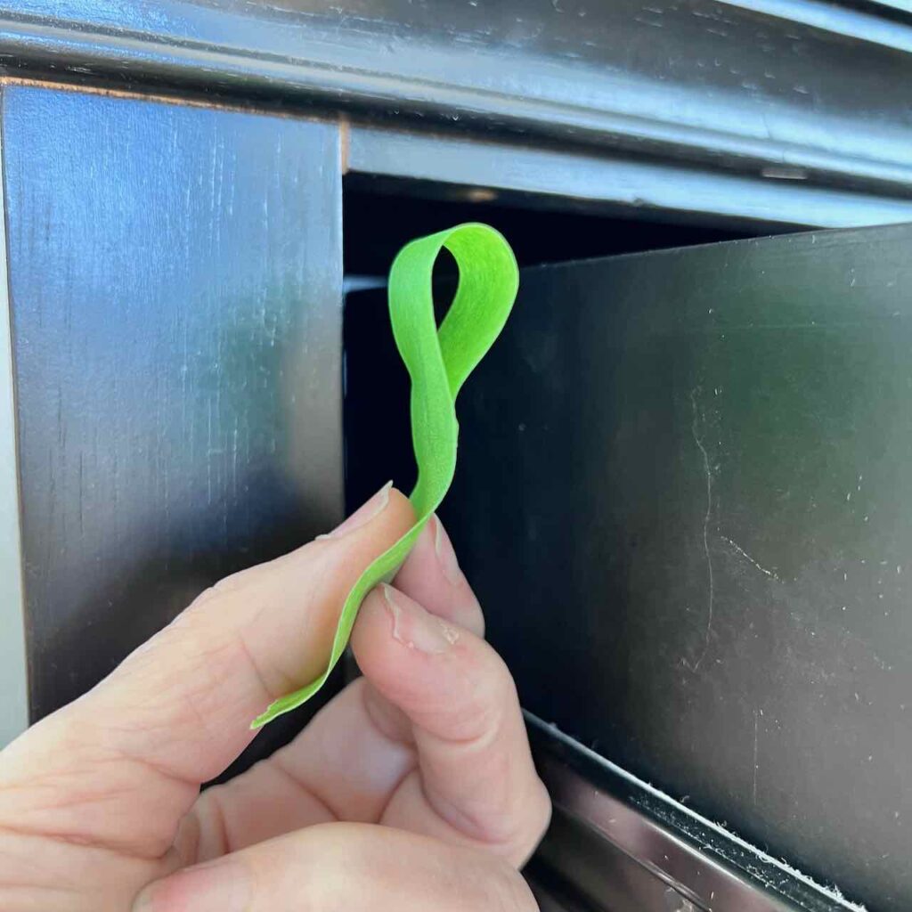 woman's finger holding loop of painters tape