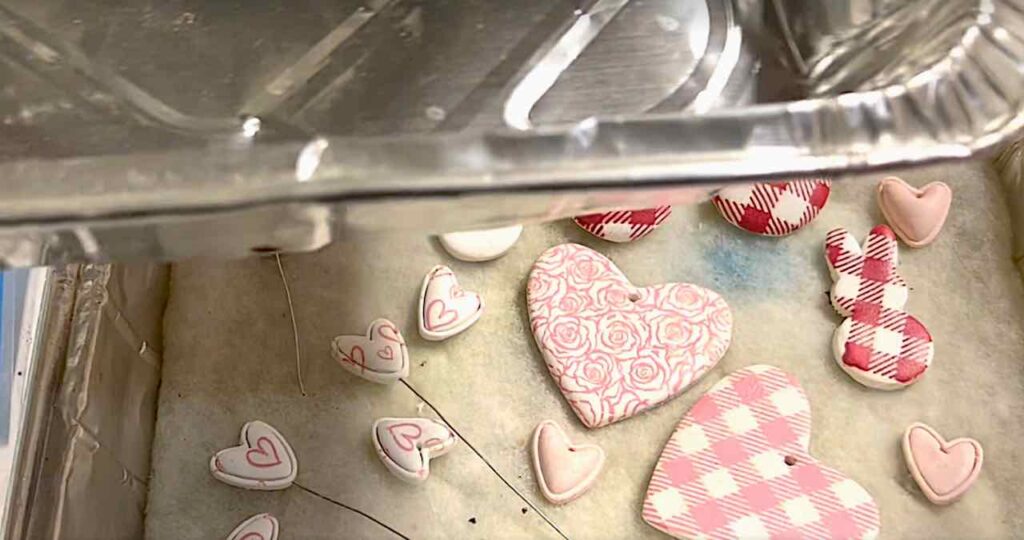 assortment of screen-printed polymer clay hearts on batting in a tray to be cured in the oven