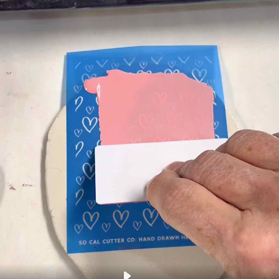 hand pulling paint over the screen with a plastic card