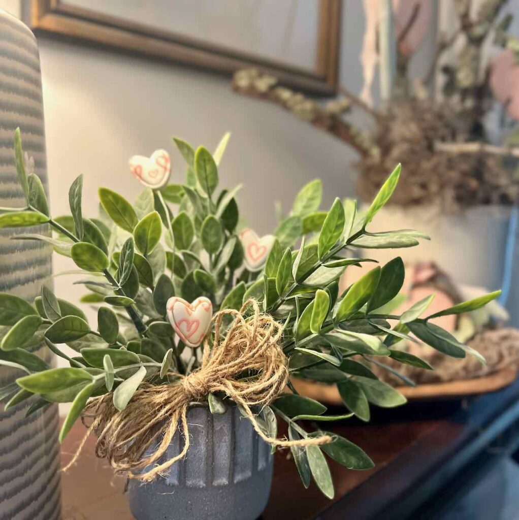 three small screen-printed clay hearts are accents in a house plant