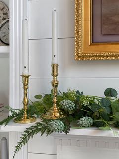 candles and greenery on the corner of a mantel