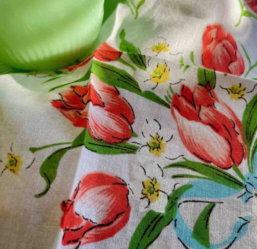 Closeup of vintage hanky printed with bright tulips with a apple green vase