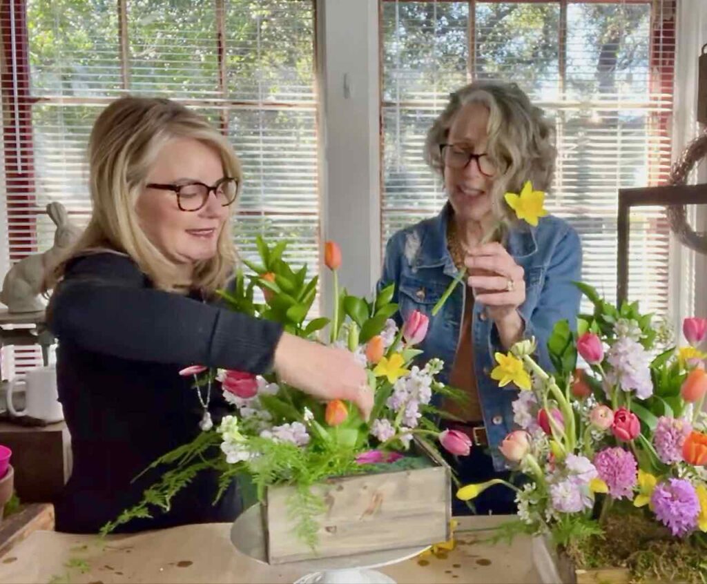two women adding Daffodils to the Easter flower arrangement