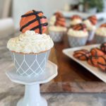 closeup of a basketball cupcake on a pedestal with and cookies in the background