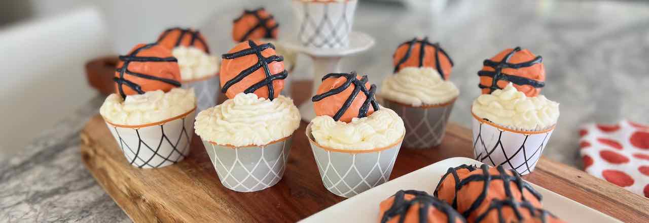 wide closeup of basketball cookies on a plate and as cupcake toppers