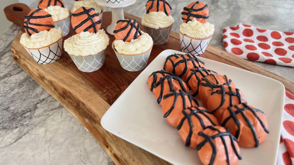 Basketball meringue cookies in front of cupcakes with basketball toppers