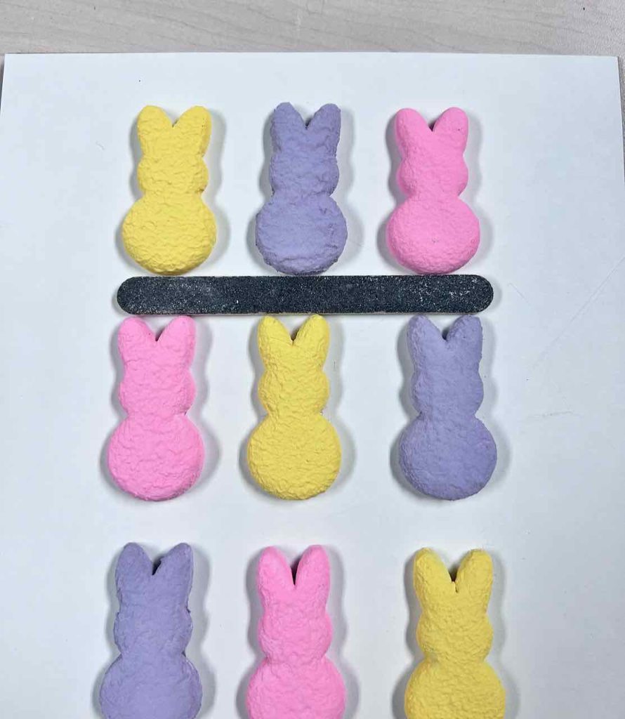 Finished clay bunnies lined up on a board with a nail file between the rows
