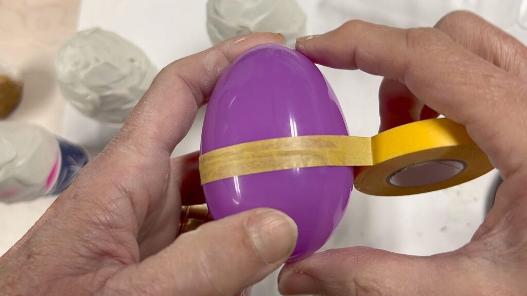 two hands holding a plastic Easter egg and taping over the seam