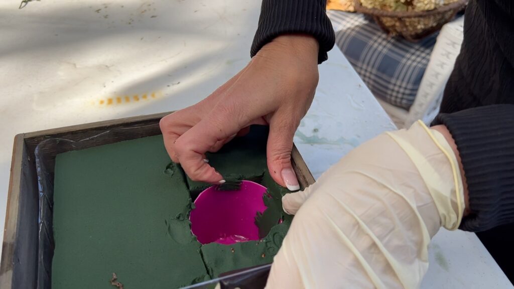 woman's hands pushing the last piece of foam in a wood box planter what has a cup for styrofoam already glued in place 