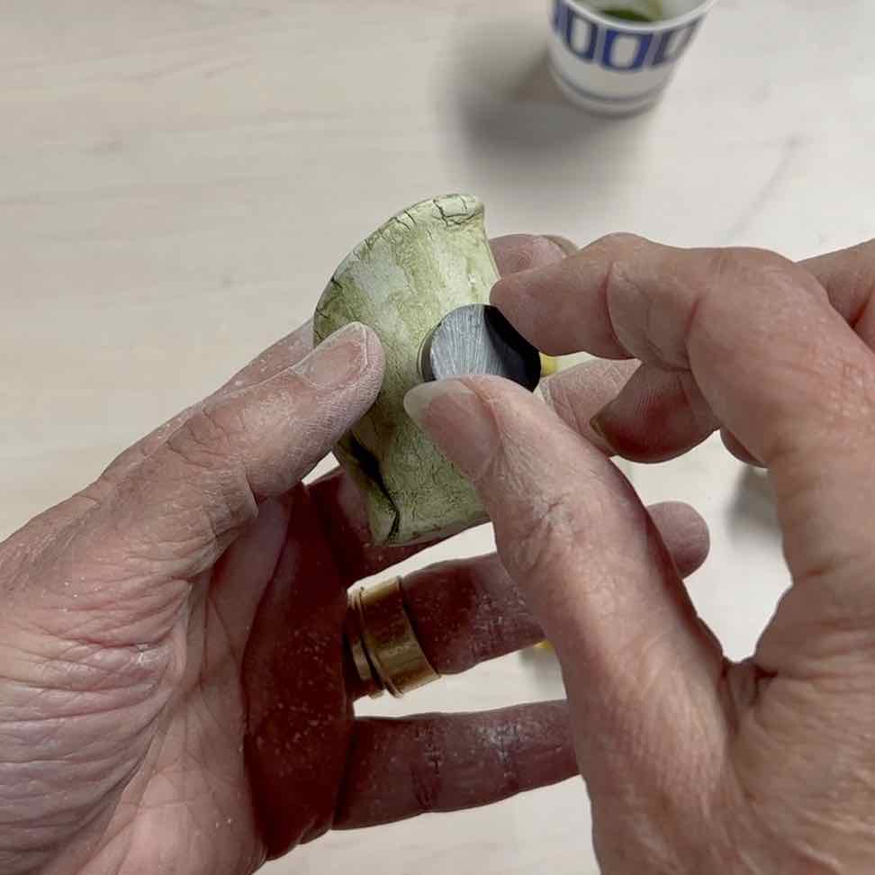 closeup of hands holding a magnet on the back of the finished pot