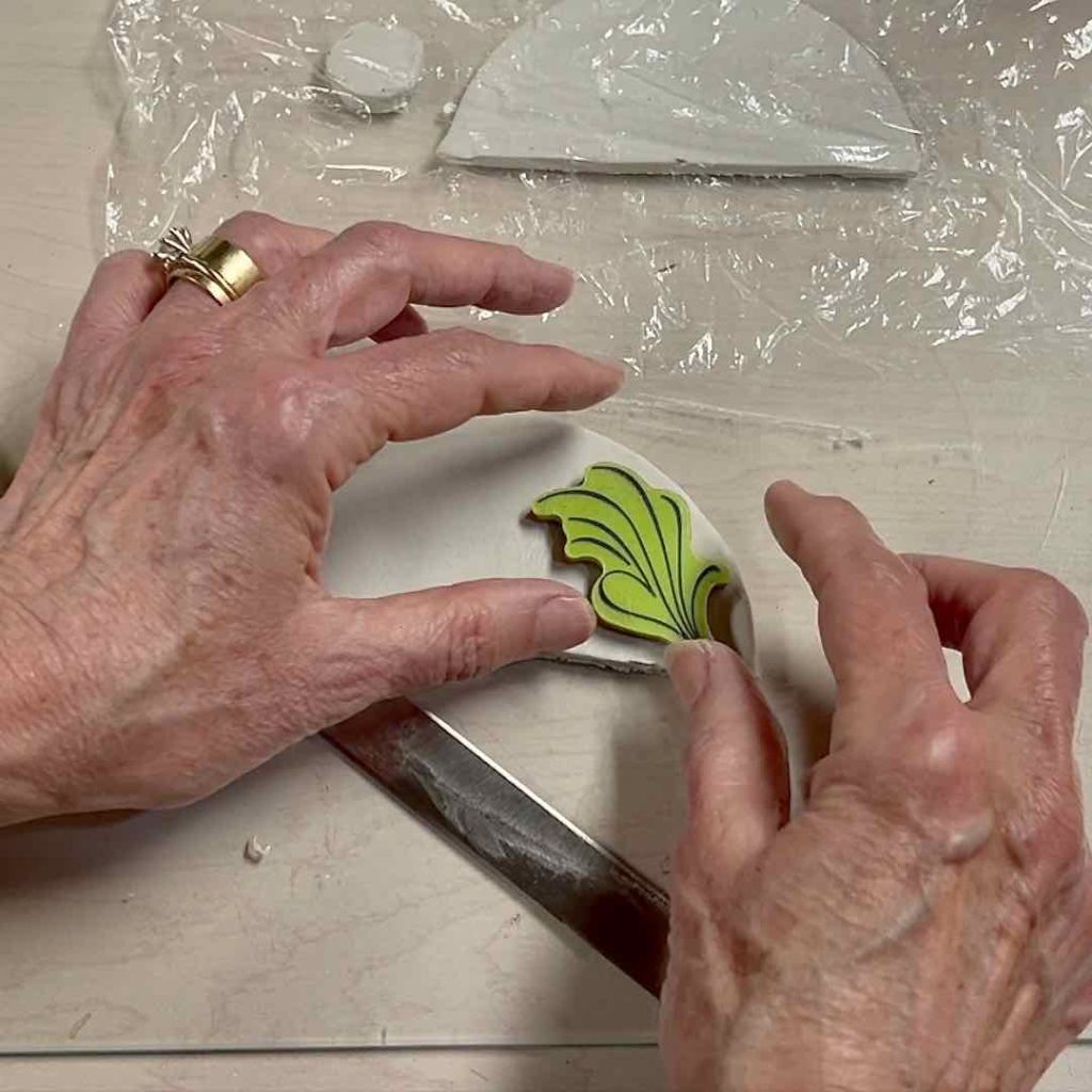 closeup of hands applying a rubber stamp to the clay