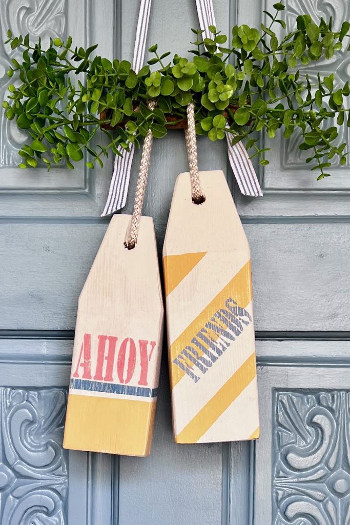 Two decorative wooden buoys that say "Ahoy " and "Friends" hanging on a front door