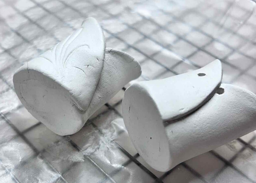 closeup of two clay pots on their backs drying on wax paper on. cooling rack