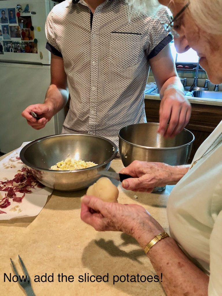 closeup of a grandmother teaching her grandson how to peel potatoes