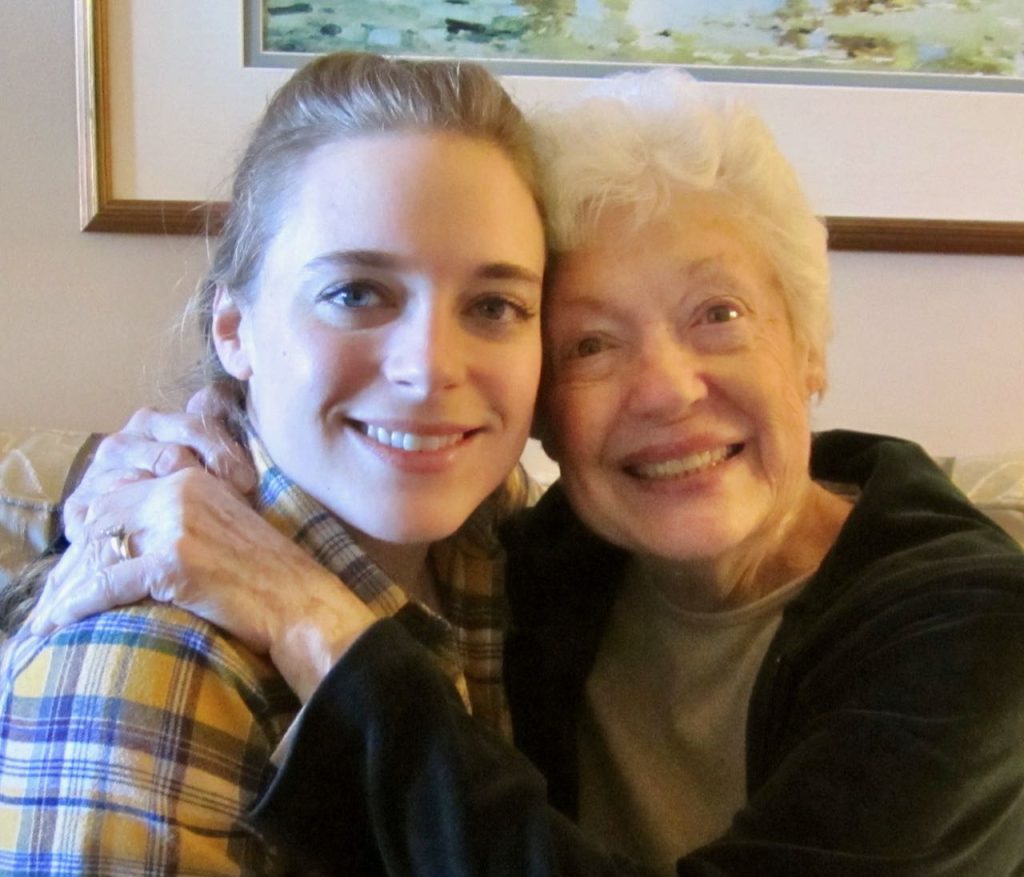 A smiling grandmother holding her smiling grown daughter very tightly