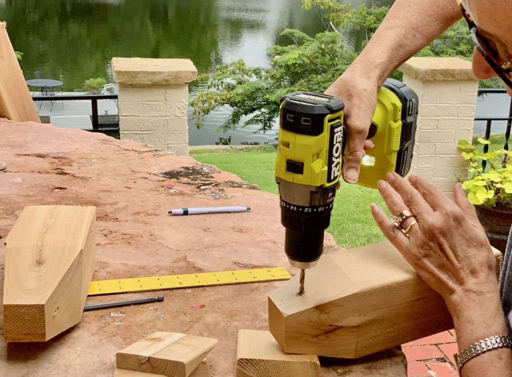 woman's hand drilling a hole into the top of a wood buoy