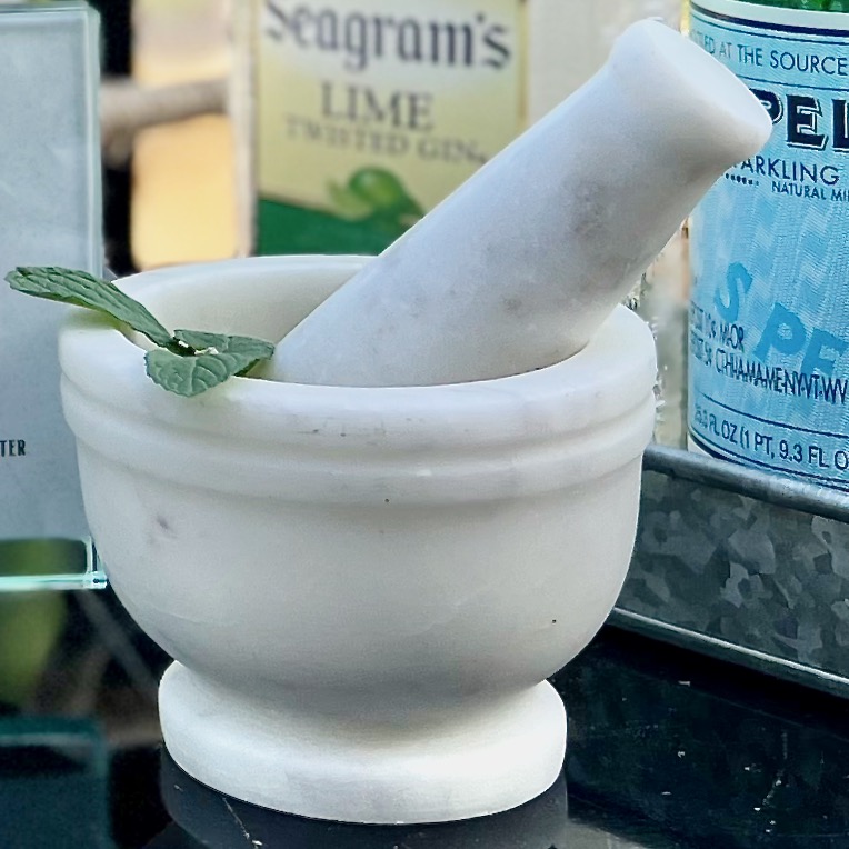 closeup of marble mortar and pestle set with mint leaves